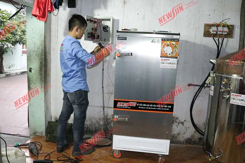 Nhân viên kỹ thuật NEWSUN lắp đặt tủ nấu cơm cho khách hàng